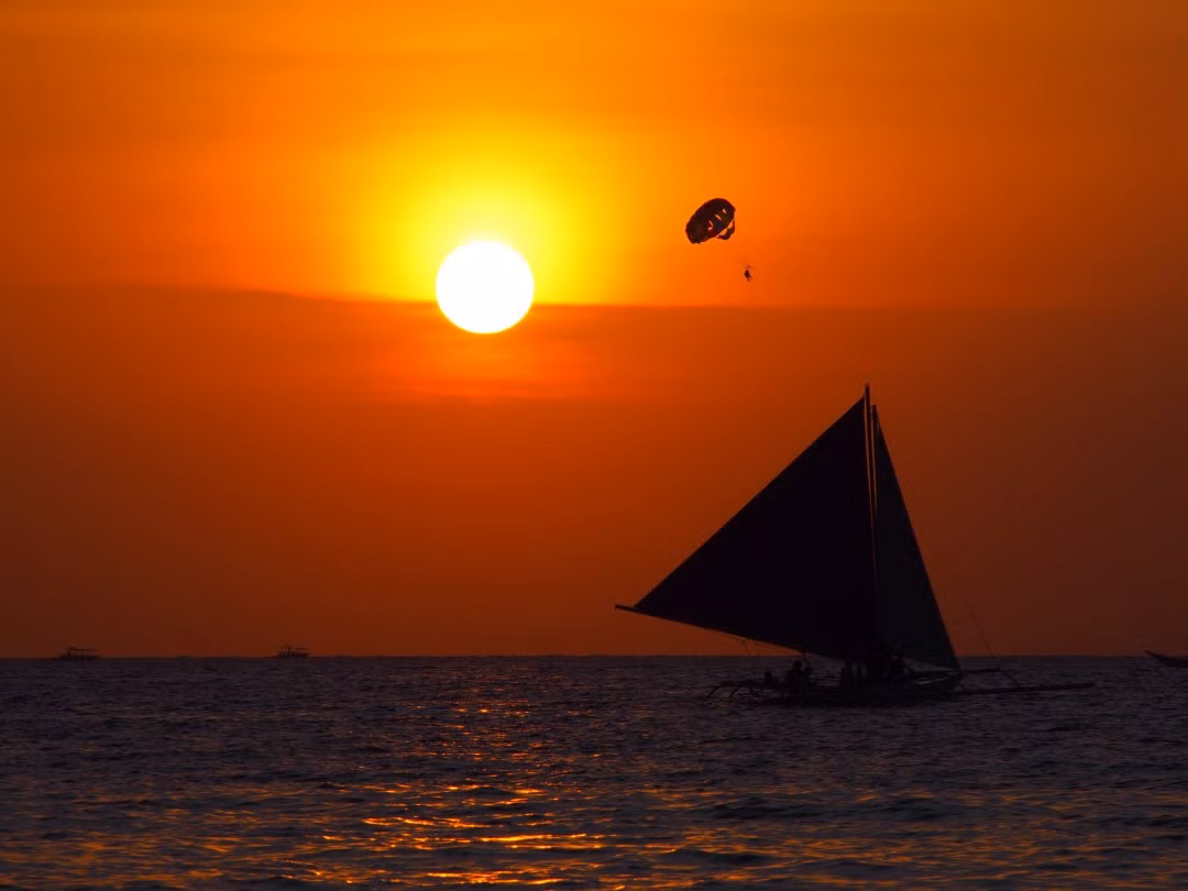 Thật thú vị khi vừa ngồi trên bãi cát trắng tại Boracay, Philippines vừa ngắm mặt trời lặn phía sau những chiếc thuyền.