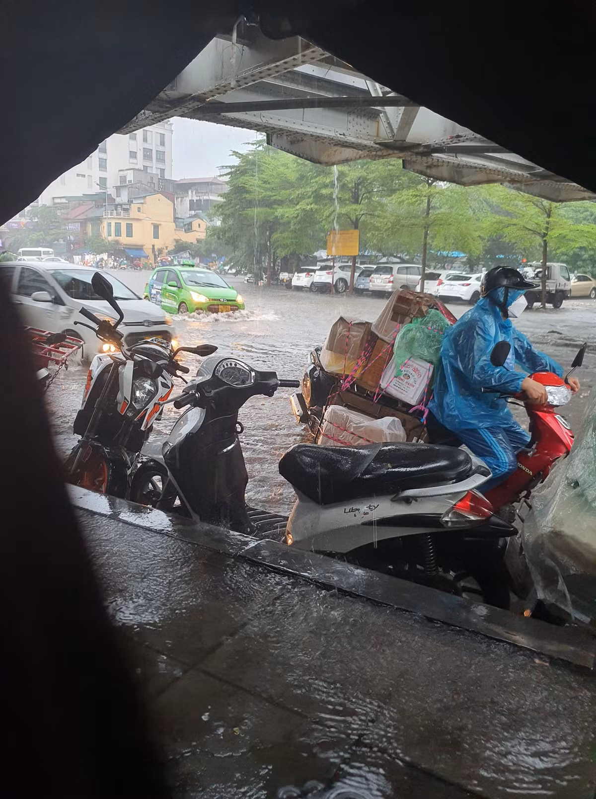 Mưa lớn khiến các phương tiện xe máy phải dừng trú mưa.