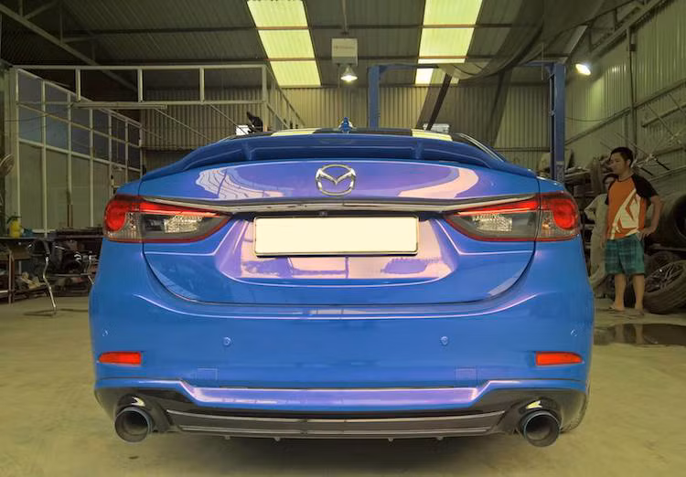 Cản sau nguyên bản của Mazda 6 cũng được QS Performance giữ nguyên, chỉ cải tiến bằng cách nẹp bên dưới và "trổ" thêm các khe gió "giả" ở hai bên. Hệ thống xả của chiếc xe cũng đã được độ lại với chụp khò 7 màu. Nằm bên trên nắp khoang hành lý là cánh đuôi dạng nẹp nhỏ gọn.