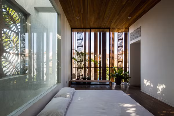 Phòng ngủ ngập ánh sáng có điểm nhấn là cửa gỗ xoay họa tiết lá.