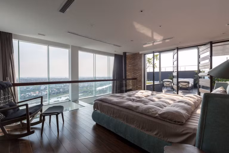 Phòng ngủ thoáng rộng với tường kính lớn nhìn ra không gian rộng.