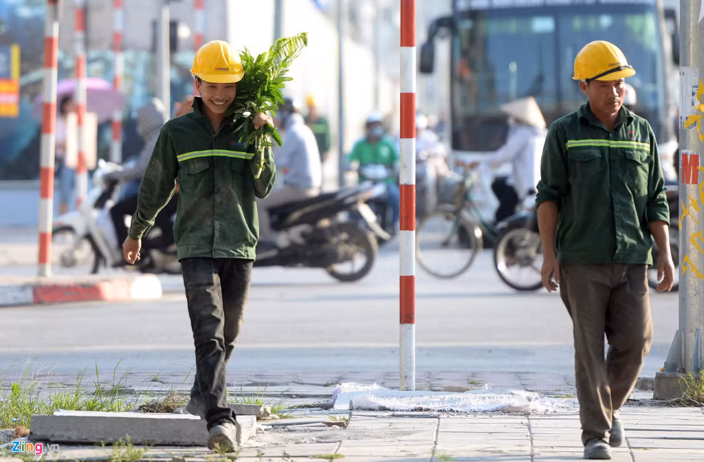 Anh Nguyễn Văn Sang (công nhân thi công một tòa nhà trên đường Trần Duy Hưng) phải dùng tán lá của cành cây bên đường để che nắng khi đi bộ về nghỉ trưa từ công trường. Ảnh: Quỳnh Trang.