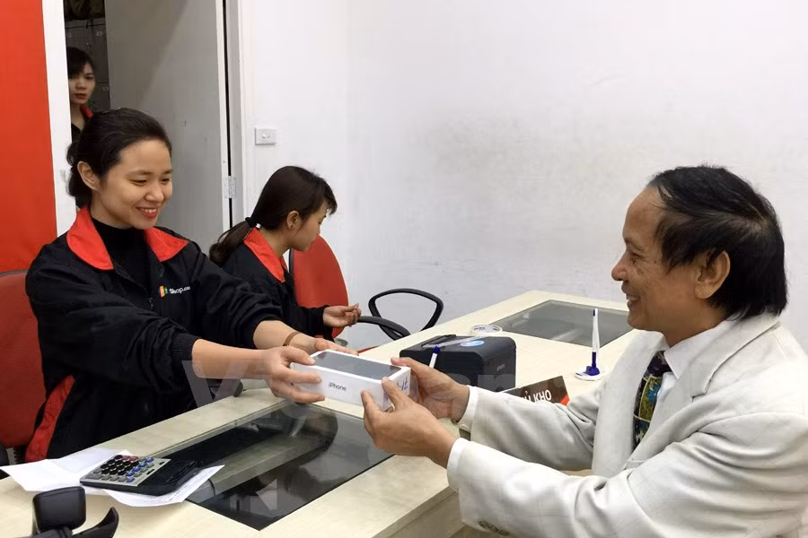 Bác Trần Long, 70 tuổi là một trong những khách hàng nhận máy sớm nhất tại FPT Shop Thái Hà. (Ảnh: T.H/Vietnam+)