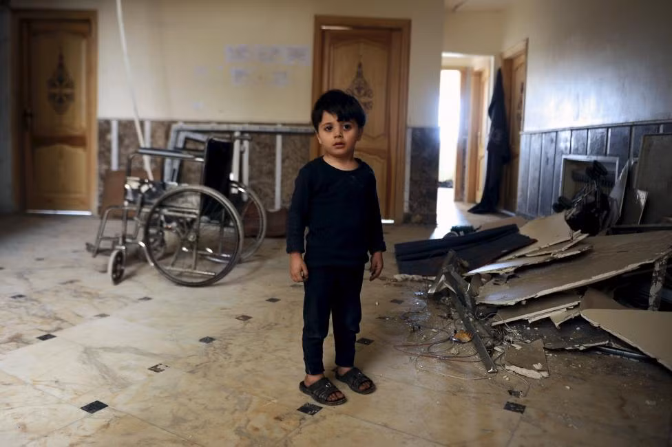 Bé trai đang bên trong một bệnh viện ở ngoại ô quận Sayeda Zeinab, nam Damascus, Syria. Em cùng những người khác được đi di tản khởi hai thị trấn Foua và Kefraya.