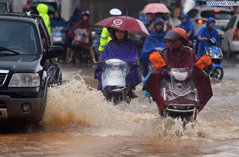 Mọi người di chuyển phương tiện trên con đường ngập nước lênh láng.