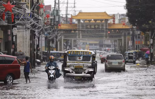 Phương tiện giao thông di chuyển qua con đường ngập nước do bão Noc-ten gây ra ở thành phố Quezon ngày 26/12. Ảnh inquirer.net