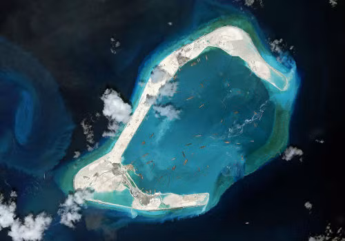 Ảnh chụp vệ tinh bãi Đá Subi (Subi Reef) tháng 8 năm 2015. Theo báo Anh The Guardian, Trung Quốc bồi đắp các đảo để xây trên đó các đường băng, đồn bốt và cả những thị trấn nhỏ, gây nguy hại cho các hệ sinh thái biển vốn mang tính thiết yếu trong việc duy trì trữ lượng thủy sản và tính đa dạng sinh học.