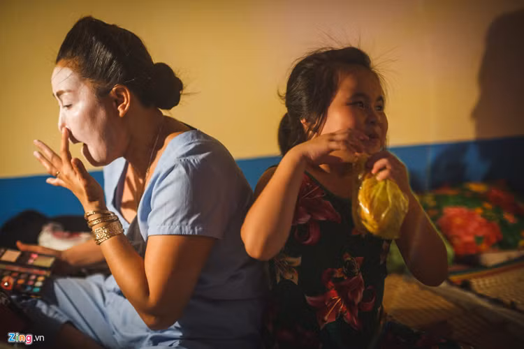 Gần đó, nghệ sĩ Băng Kiều (con gái của nghệ sĩ Hề Lạc) cũng đang vẽ mặt, trong khi cô con gái Lê Yến Nhi (8 tuổi) đang chơi đùa. Bé được đi theo mẹ lưu diễn trong thời gian nghỉ hè.