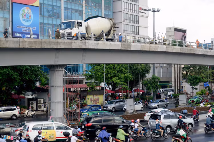 Phía trên xe bồn đổ bê tông lan can, công nhân khẩn trương làm việc, phía dưới giao xe cộ lưu thông qua khu vực này bình thường.