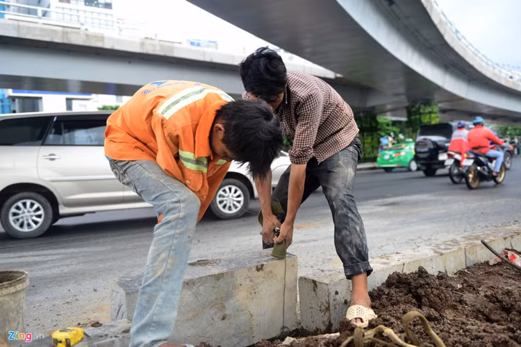 Hai công nhân lắp tảng đá lan can khu khuôn viên trước nhà ga quốc nội.