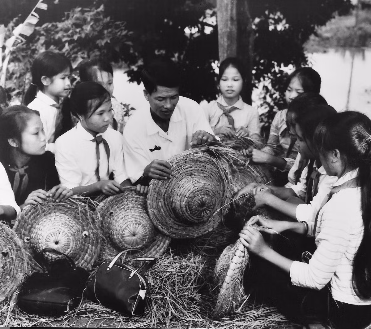 Giáo viên Trường cấp 2 Dịch Vọng, Từ Liêm, hướng dẫn học sinh đan mũ rơm phòng tránh bom bi. Ảnh: Tư liệu.