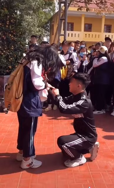 Trước đó, cư dân mạng từng tranh cãi về clip khác khi nữ sinh được cầu hôn ngay tại trường. Cụ thể, trong bộ quần áo thể dục của học sinh cấp 3, cậu học trò bảnh bao đã mạnh dạn nắm lấy tay "crush" rồi quỳ xuống trong sự ngỡ ngàng của mọi người. Ảnh: Tiin.vn