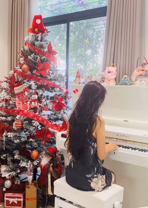 Vân Hugo đánh đàn bên cây thông Noel dịp Giáng sinh.