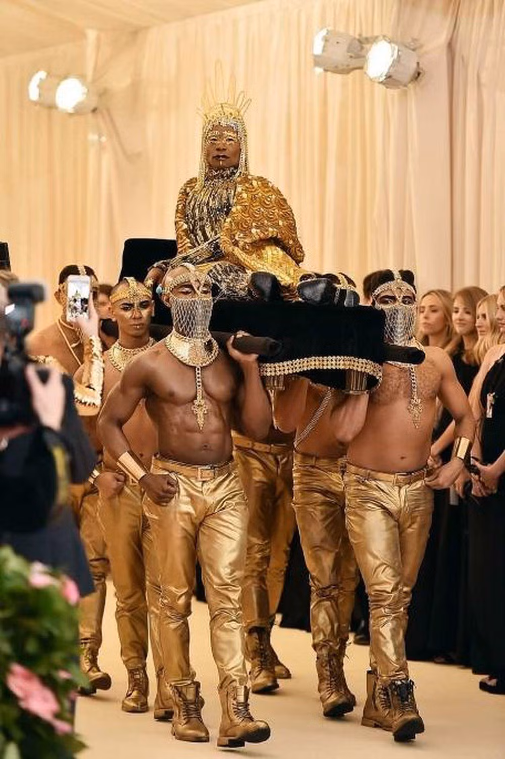 Hình ảnh trên khiến nhiều người nhớ đến màn xuất hiện của Billy Porter trên thảm đỏ Met Gala 2019 khi anh được cả một dàn các cận vệ trong trang phục màu vàng kim khênh trên một chiếc kiệu giường như một vị Pharaoh của Ai Cập cổ đại.