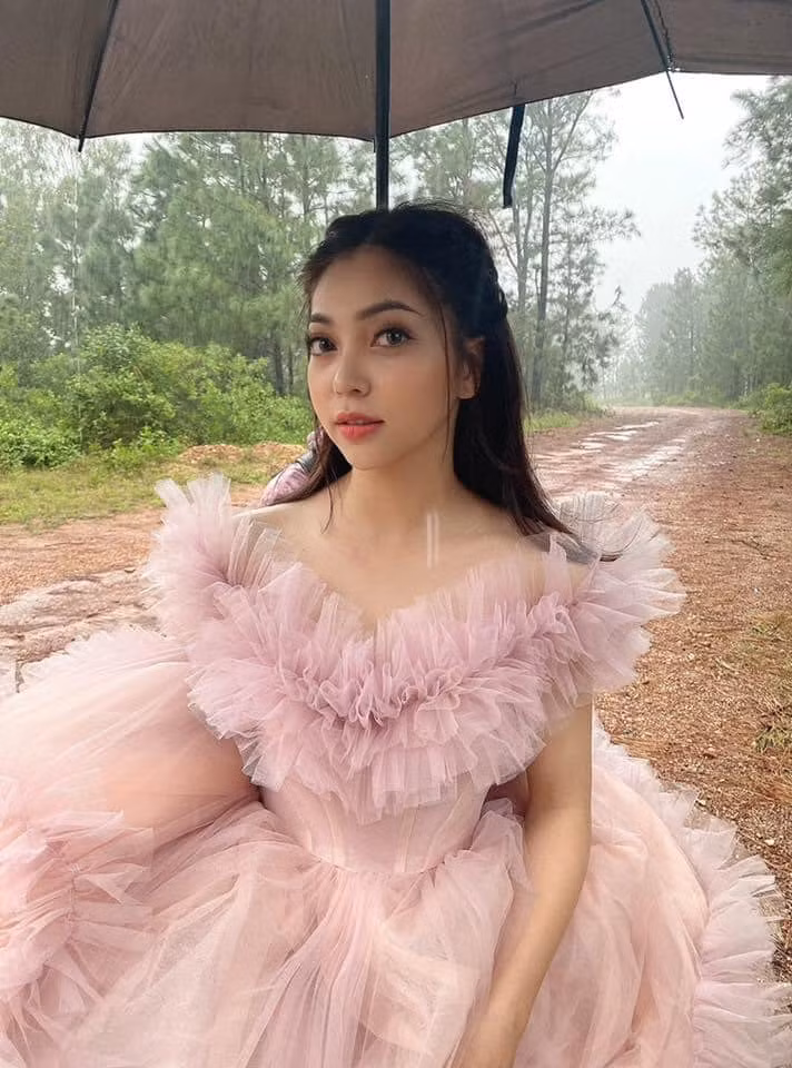 Hậu trường ghi lại Nhật Lê mặc một chiếc váy màu hồng, xung quanh là nhân viên studio đang tận tình chỉnh sửa trang phục. Ảnh: Facebook