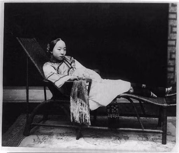 Một phụ nữ Trung Quốc mặc trang phục truyền thống, ngồi nghỉ trên chiếc ghế dài. Chân người này nhỏ xíu do tục bó chân, một tập tục thịnh hành ở Trung Quốc thế kỷ 19. Ảnh tư liệu.
