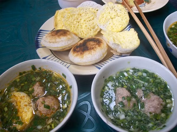 Cái ngon nhất của bánh căn là chấm ngập cặp bánh còn nóng hôi hổi vào chén nước chấm, rồi cắn một miếng bánh đã thấm nước chấm nồng vị ớt, béo ngậy mùi hành phi.