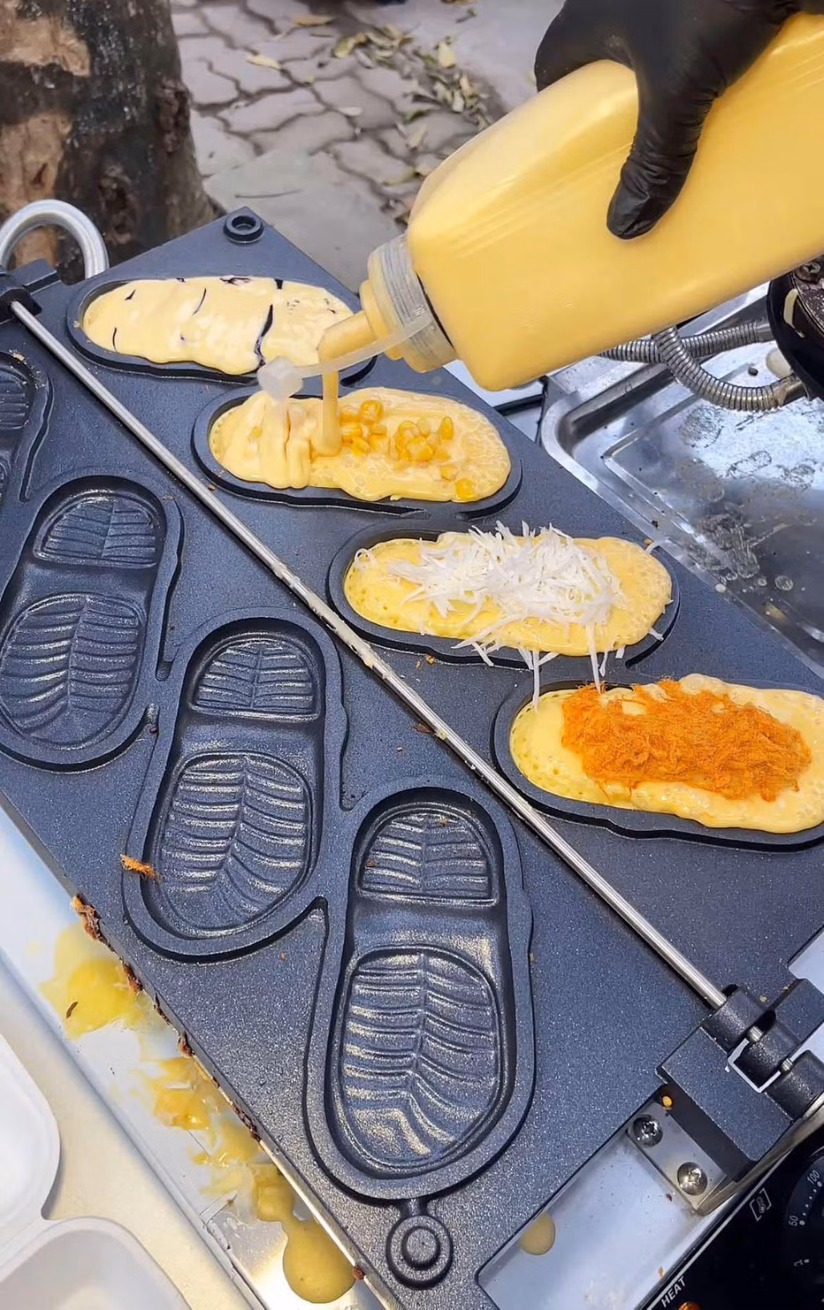 Khi đổ bột, những chiếc bánh trông khá bình thường nhưng chỉ sau 4 phút nướng, chúng sẽ "biến hình" thành những chiếc dép nhỏ xinh, vàng ruộm, giòn rụm.