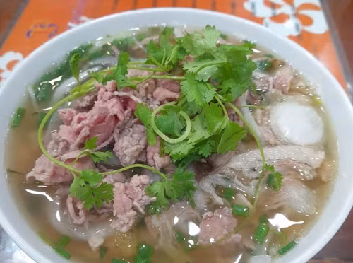 Khác với nước phở truyền thống, Phở 10 Lý Quốc Sư không trong vắt mà ngả vàng vừa có vị béo của các loại xương ninh lâu, vừa có vị ngọt thanh tự nhiên. Đặc biệt, bánh phở của quán được tự làm, màu trắng trong kết hợp với thịt bò tươi rói, đậm vị khiến thực khách ăn một lần sẽ nhớ mãi. (Ảnh: Tripadvisor)