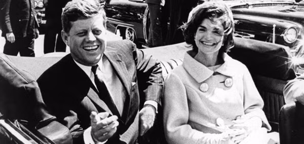 Khi đoàn xe đi ngang Dealey Plaza, một tay súng đã ám sát Tổng thống Kennedy. Phát súng thứ nhất bắn trượt xe chở ông chủ Nhà Trắng.