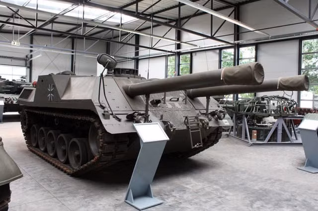 Đầu những năm 1970, công ty chuyên lĩnh vực sản xuất xe bánh xích, động cơ diesel Maschinenbau Kiel GmbH (MaK) được giao nhiệm vụ phát triển một loại xe tăng không tháp pháo, phải có 2 nòng pháo. Kiểu xe tăng như vậy đi theo lối mòn thiết kế các loại pháo chống tăng tự hành trong chiến tranh Thế giới thứ 2. Chính vì tư duy như vậy của MaK đã khiến cho nước Anh – tham gia bỏ tiền cho chương trình nghiên cứu từ bỏ Đức bởi họ không thích kiểu thiết kế tăng không tháp pháo như vậy, họ mong muốn một truyền thông hơn. Nguồn ảnh: WHO