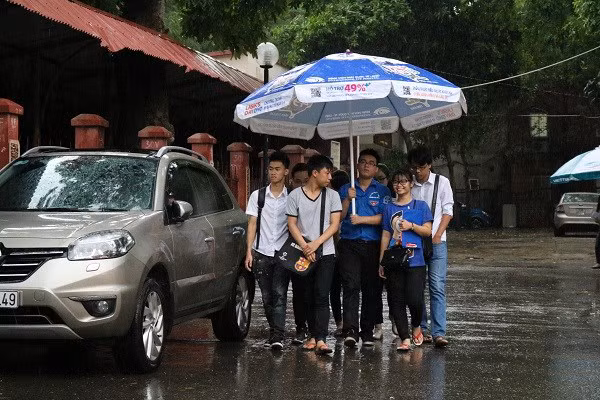 Các thí sinh rời phòng thi trong cơn mưa chiều 2/7 tại Hà Nội.