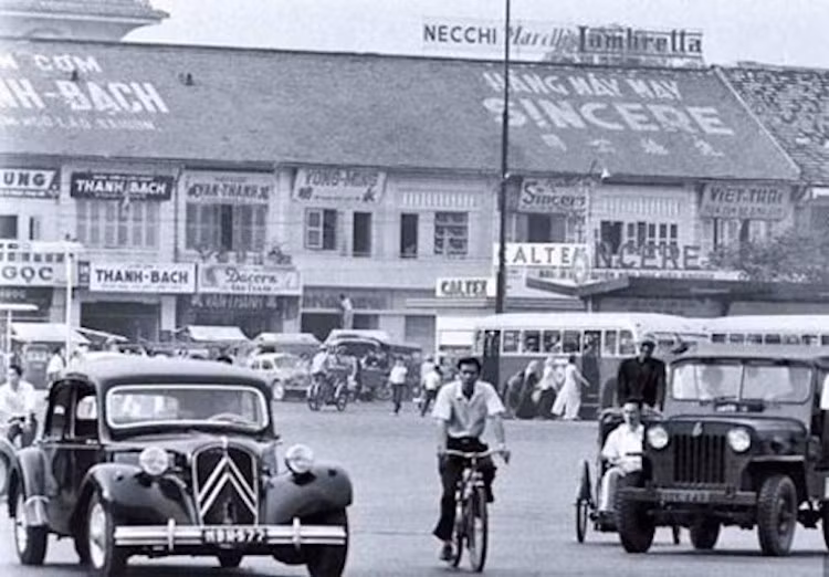 Người đi xe đạp nằm "lọt thỏm" giữa Citroen "Tắc-xông" Traction và xe Jeep quân sự. Ở phía sau, trên mái một tòa nhà có bảng hiệu của hãng xe máy Lambretta, chứng tỏ thương hiệu này cũng đã xuất hiện rất sớm tại Sài Gòn trước khi quay trở lại Việt Nam trong Thế kỷ 21.