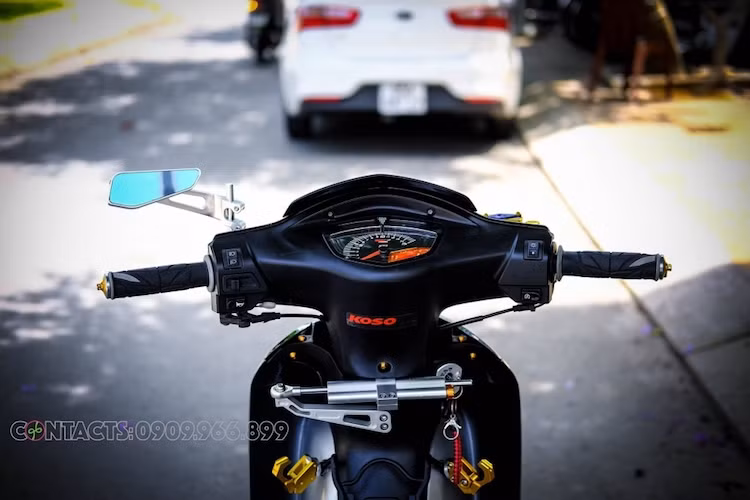 Cụm đồng hồ điện tử KOSO vốn dành cho Yamaha Exciter 135 đời 2010 đã được chế mủ một cách khéo léo và gọn gàng "như zin" trên tay lái của Wave, bên dưới là cây trợ lực Ohlins tem khắc khiến chiếc xe ổn định hơn khi chạy tốc độ cao. Ngay cả những móc treo đồ hai bên thân xe cũng được làm bằng nhôm nhuộm vàng.