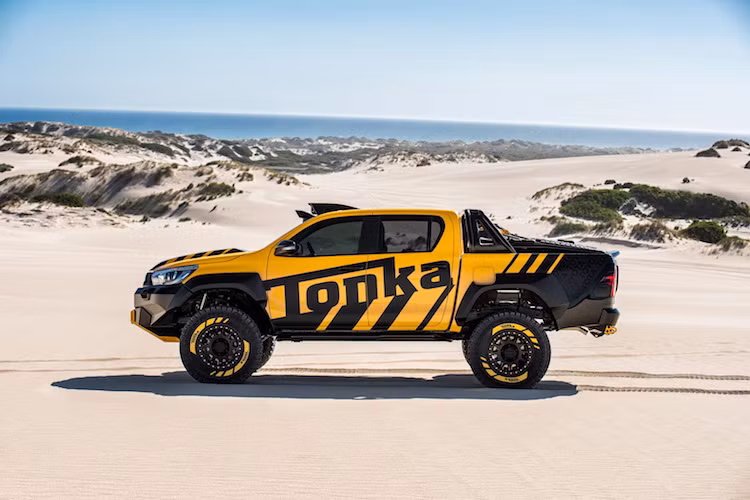 Ở hai bên thân xe, các vòm bánh của Hilux Tonka đã được nới rộng để có thể chứa vừa những bánh xe với lốp offroad chuyên dụng. Bên cạnh đó, chiếc xe cũng có khoảng sáng gầm lớn hơn Hilux nguyên bản tới 150 mm nhờ có hệ thống treo offroad đặc chủng.