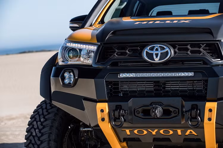 Tuy nhiên không chỉ dừng lại ở màu sơn, mẫu xe Hilux Tonka còn được độ thành một chiếc bán tải offroad bền bỉ và có ngoại hình cực "ngầu". Toàn bộ phần cản trước nguyên bản của Hilux đã được thay bằng ba-đờ-sốc đầy góc cạnh và thích hợp tời điện, móc kéo cùng đèn LED. Nằm bên trên phần đầu xe là nắp ca-pô cơ bắp với khe hút gió được "trổ" thêm và đèn LED trên mui xe.