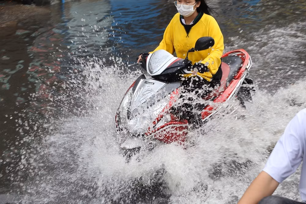 Nước ngập lênh láng, văng tung tóe khi người dân chạy xe qua