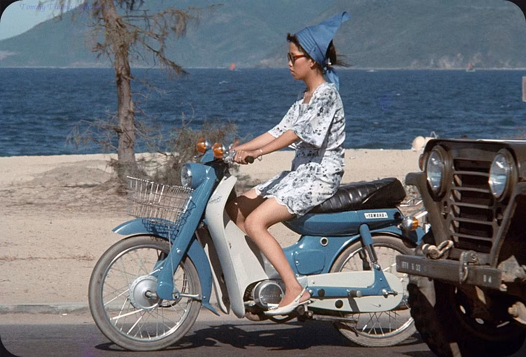 Vẫn là một chiếc xe Yamaha Dame màu xanh dương, nhưng lần này người cầm lái là một thiếu nữ tân thời.