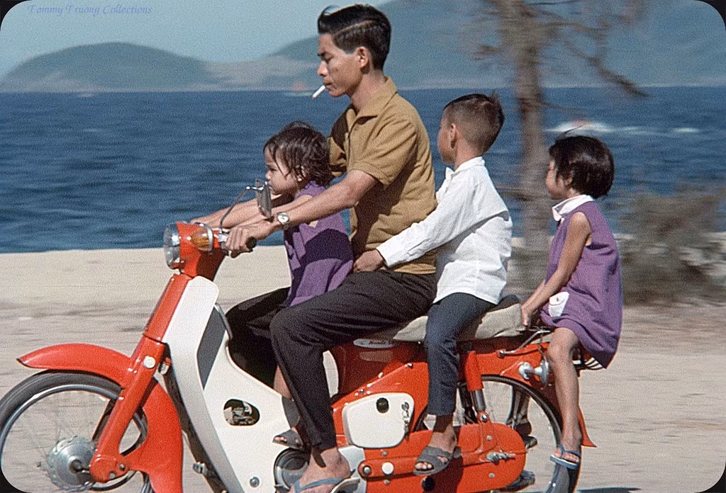 Người đàn ông và ba em bé trên chiếc Honda Dame C50 màu đỏ.