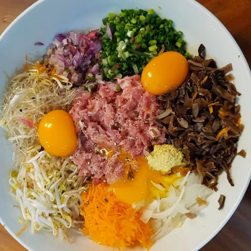  Sơ chế nguyên liệu và làm nhân nem rán: Thịt lợn mua về bạn rửa sạch, rồi băm nhuyễn. Tiếp theo, mang giá đỗ đi rửa sạch, rồi vắt kiệt nước. Cà rốt, hành tây sau khi loại bỏ vỏ và rửa sạch, bạn thái sợi. Hành lá thái nhỏ. Ngâm mộc nhĩ với nước ấm trong vòng 15 phút cho nở mềm, sau đó rửa sạch rồi băm nhỏ. Miến trần nhanh qua nước sôi cho sợi mềm ra, rồi lấy kéo cắt thành đoạn nhỏ. Ảnh minh họa