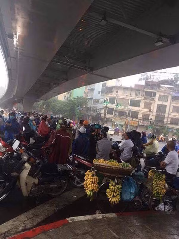 Dòng người đứng trú mưa dưới chân cầu vượt tại khu vực Kim Ngưu, khiến khó khăn trong việc đi lại.