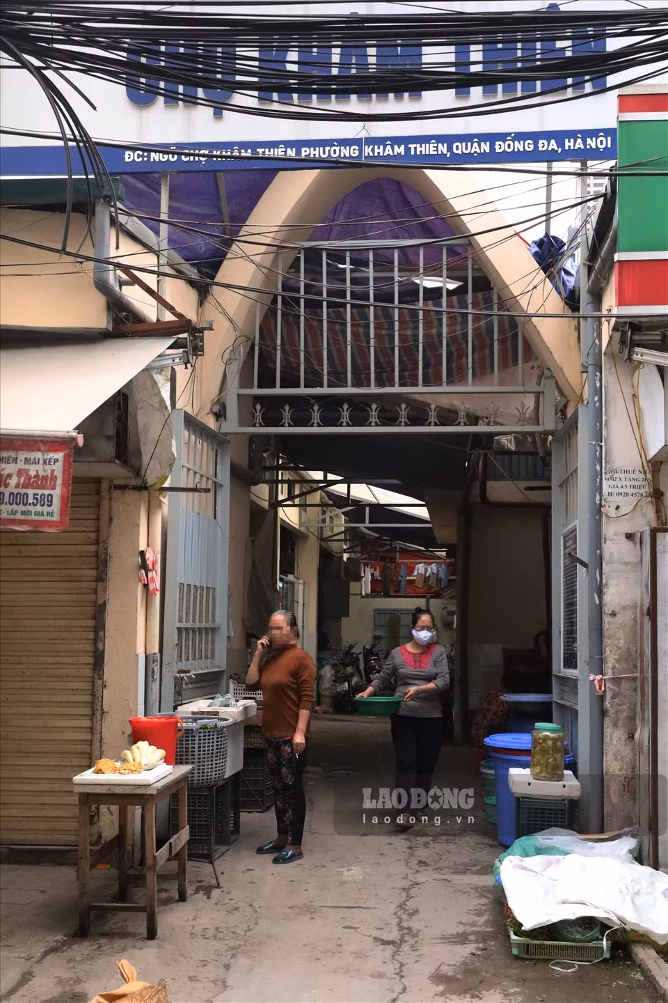 Người phụ nữ chủ quan không đeo khẩu trang, vô tư đi lại quanh khu vực cổng chợ Khâm Thiên (Đống Đa, Hà Nội).