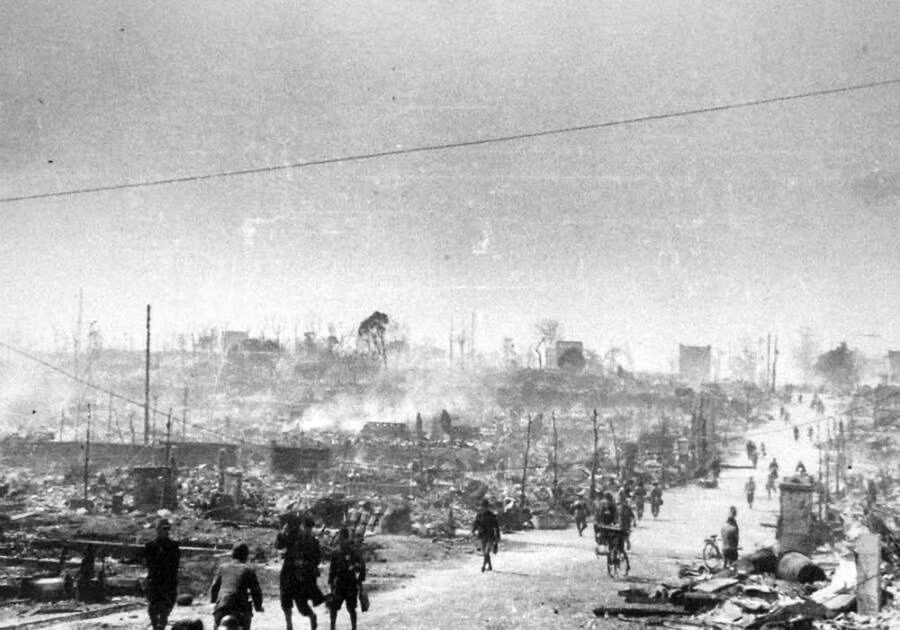 Nhiều người dân Nhật Bản đi trên một con đường ở gần Ushigome Ichigaya, Tokyo hồi tháng 4/1945. Hai bên đường là những ngôi nhà gần như bị phá hủy hoàn toàn.