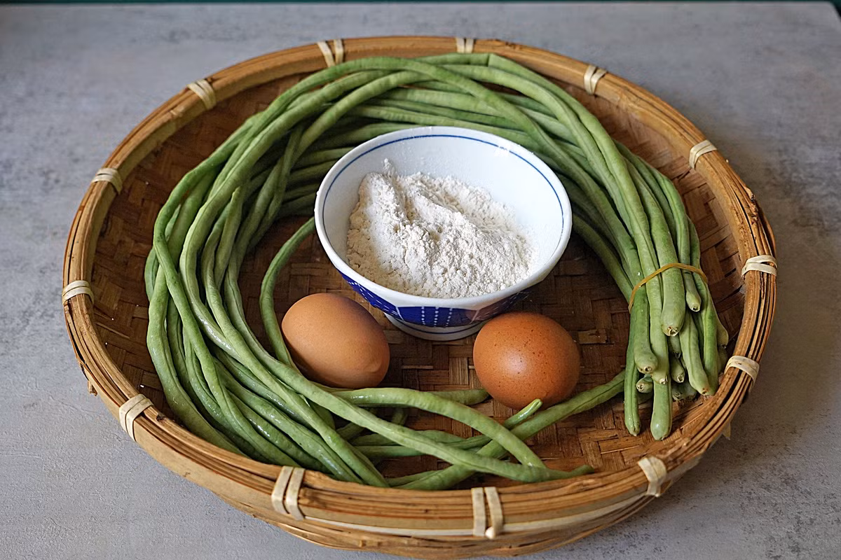 Nguyên liệu: 400g đậu đũa, nửa bát con bột mì, 2 quả trứng, 1 thìa cà phê muối, chút tiêu. Bước 1: Chuẩn bị đậu đũa, bột mì, trứng và các nguyên liệu khác trước. Lưu ý: Đậu đũa phải tươi và mềm.