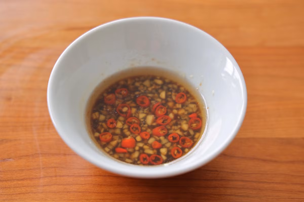 Bước 5: Băm nhỏ tỏi, ớt cho chung vào một bát, thêm chút hoa hồi vừa đủ. Đun dầu nóng rồi đổ vào bát đựng tỏi và ớt. Sau đó cho thêm tương nhạt, dấm, bột canh, đường vào trộn đều làm nước sốt.