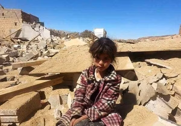 Bé gái Yemen ngồi giữa đống đổ nát.