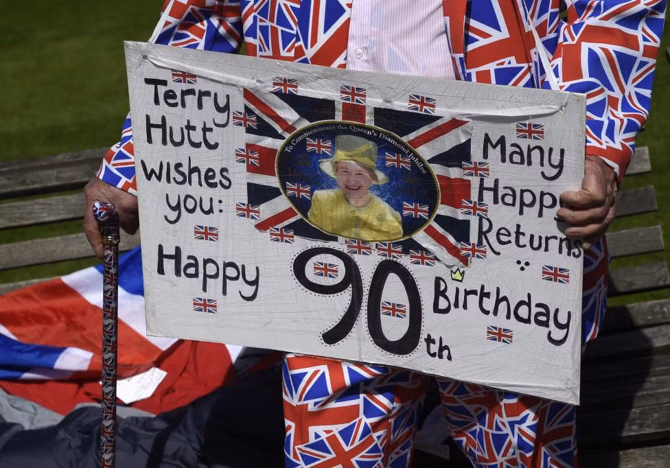 Terry Hutt cầm tấm biển chúc mừng sinh nhật lần thứ 90 của Nữ hoàng Elizabeth bên ngoài lâu đài Windsor ở Windsor hôm 20/4.