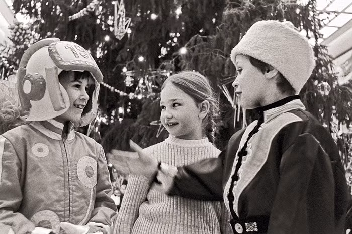 Trên đường phố, trẻ em chơi đùa bên dưới cây thông Noel khổng lồ.