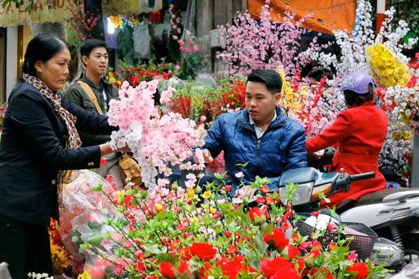 Cánh mày râu tranh thủ ghé qua chợ hoa trên phố Hàng Rươi chọn mua mấy cành hoa đào nhựa về trang trí Tết bên cạnh cây đào thật.
