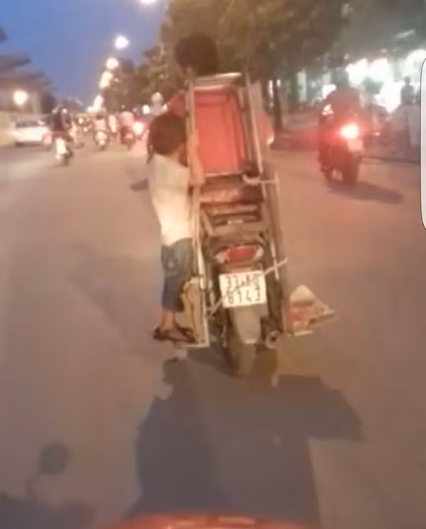 Hình ảnh cháu bé "làm xiếc" phía sau xe máy cực kỳ nguy hiểm.