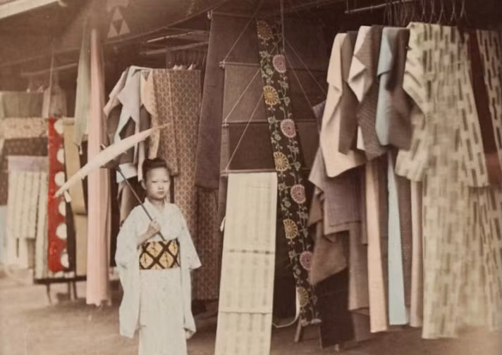 Một em nhỏ đứng trước cửa hàng quần áo vào khoảng những năm 1890. Ảnh: ATI.
