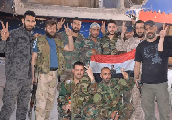 Các binh sĩ Syria giơ tay biểu tượng chiến thắng trong một bức ảnh chụp chung trên chiến trường Đông Damascus. Ảnh: FNA.