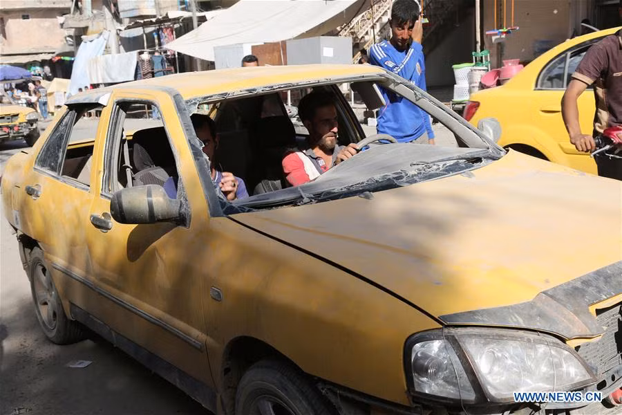 Hai người đàn ông ngồi trong chiếc ô tô không có kính chắn gió trên đường phố Tây Mosul ngày 27/5. Ảnh: THX.