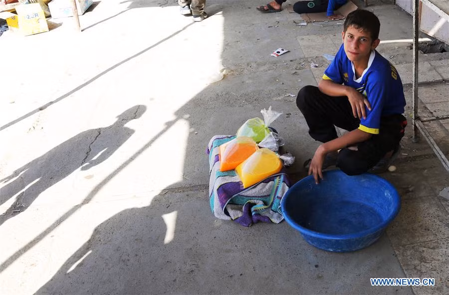 Bé trai Iraq ngồi bán những túi nước ép ở Tây Mosul. Ảnh: THX.