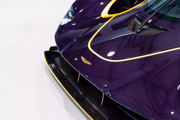Logo Aston Martin làm màu vàng, bộ mâm nhôm màu đen satin kết hợp điểm nhấn màu vàng, phần nóc xe và nắp che động cơ được làm từ sợi carbon. Toàn bộ thân xe được bọc bằng phim bảo vệ PPF, giúp giữ bề mặt đặc biệt này không bị trầy xước hay mẻ sơn. 