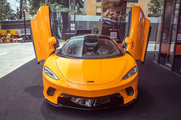 Chiếc siêu xe McLaren GT sau 1 thời gian dài định cư ở TP HCM, nay đã ra Hà Nội định cư, xe mang màu cam rất nóng bỏng. Ngoài chiếc siêu xe McLaren GT màu cam, giới đại gia Hà Nội còn mua chiếc McLaren GT màu trắng, sau đó dán nó thành màu đen nhám.